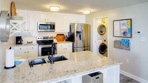 A modern kitchen with white cabinets, stainless steel appliances, a granite countertop, and a built-in oven.