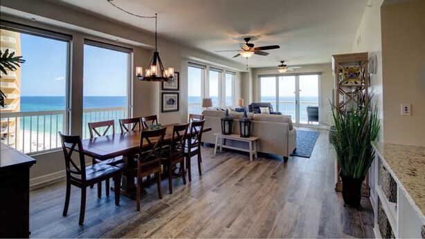 A spacious living area with a dining table, sofas, and a view of the ocean.