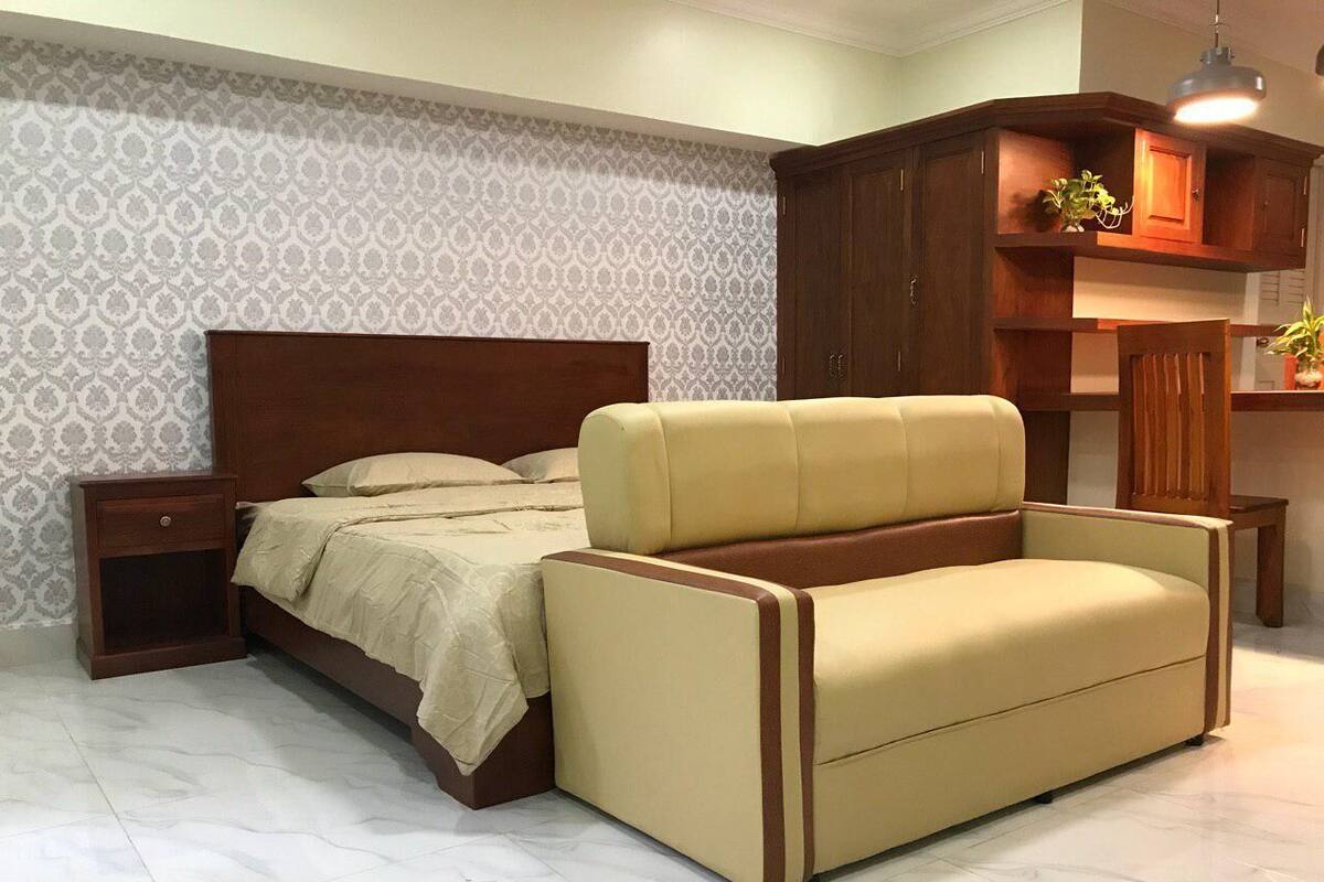 A bedroom with a bed, a nightstand, a sofa, and a wooden cabinet.
