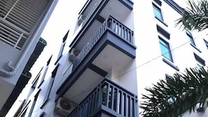 Un edificio de varios pisos con balcones, unidades de aire acondicionado y ventanas.