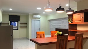 Una cocina moderna con una mesa de comedor de madera, cuatro sillas, iluminación colgante y un refrigerador.