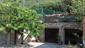Une cour avec un sol en pierre, un arbre et un bâtiment doté d’un balcon.