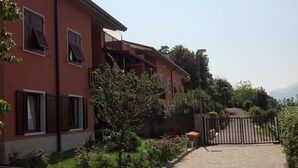 Un bâtiment rouge doté de nombreuses fenêtres et de balcons, un chemin pavé et une entrée fermée par un portail.