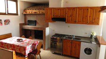 A compact kitchen with wooden cabinets, a built-in microwave, a gas stove, a sink, and a washing machine.