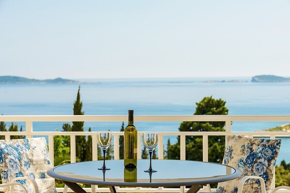 A round table with two wine glasses and a bottle on a balcony overlooking a body of water. - PENDO 2 apartment with sea view, near beaches and Dubrovnik (Mlini)
