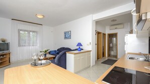 Una cocina moderna con estufa integrada, un comedor con mesa de madera y una sala de estar con sofá.