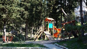 Un parque infantil con una estructura de madera para escalar, un tobogán y columpios.