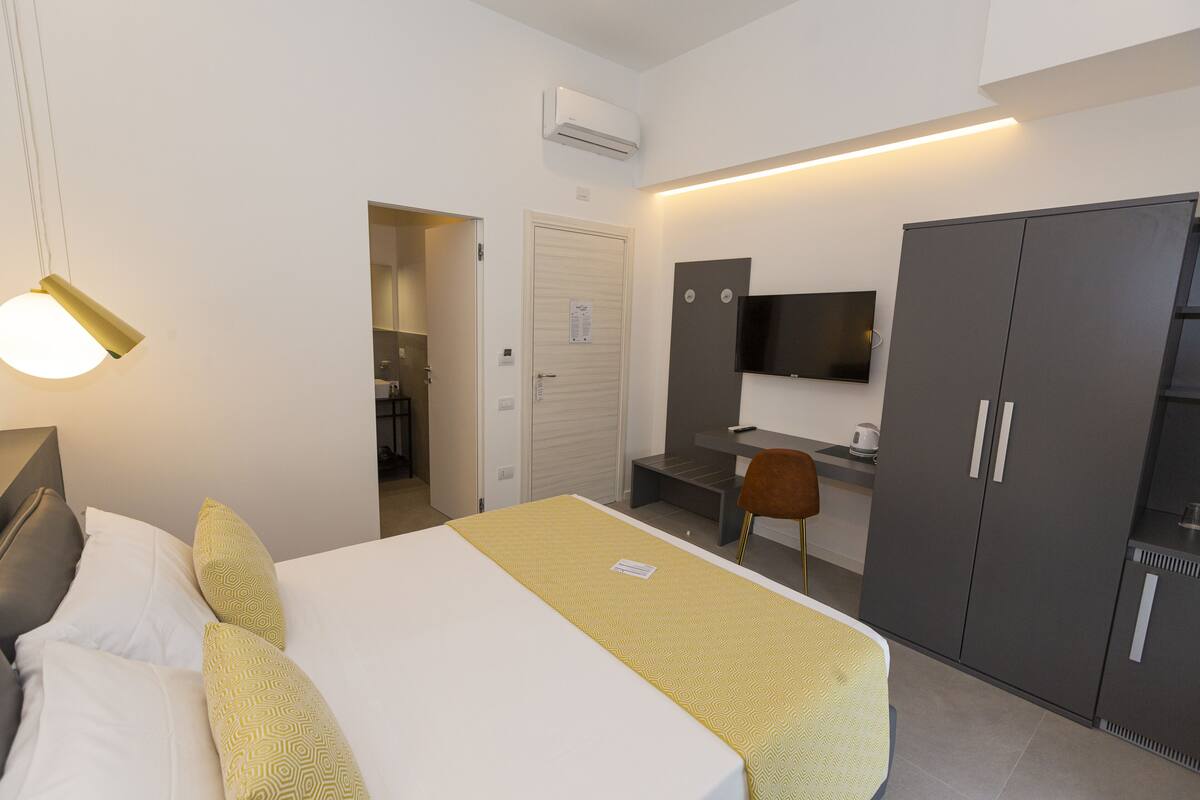 Una habitación de hotel con cama, escritorio, televisión y armario.
