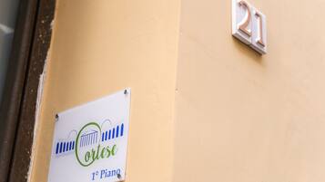 A sign with the name "Cortes" and "1º Piam" on a beige wall, next to a door with a number "21" sign.