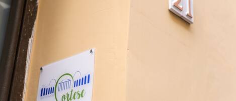A sign with the name "Cortes" and "1º Piam" on a beige wall, next to a door with a number "21" sign.