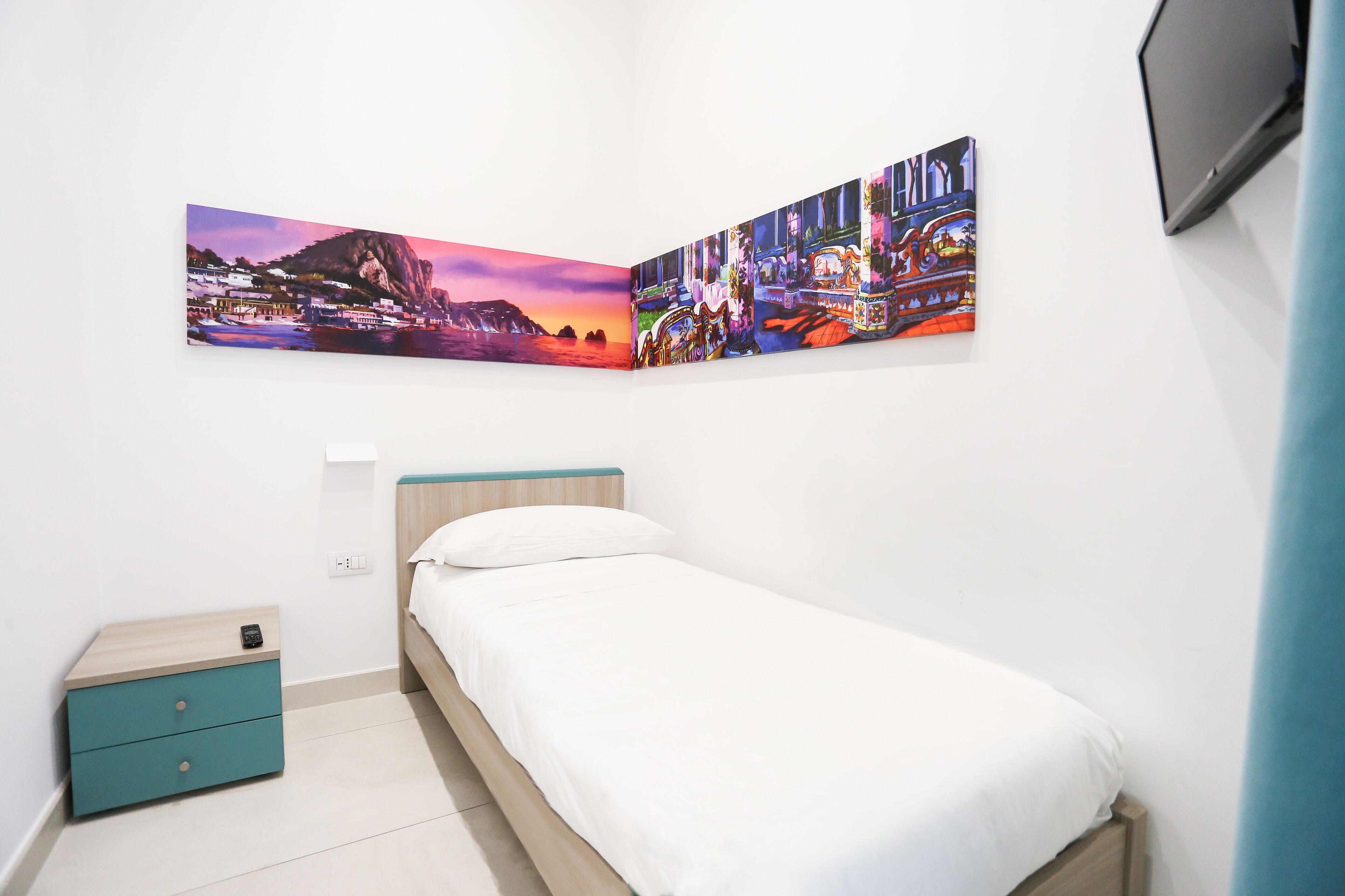 A bedroom with a bed, a nightstand, and a wall-mounted TV.