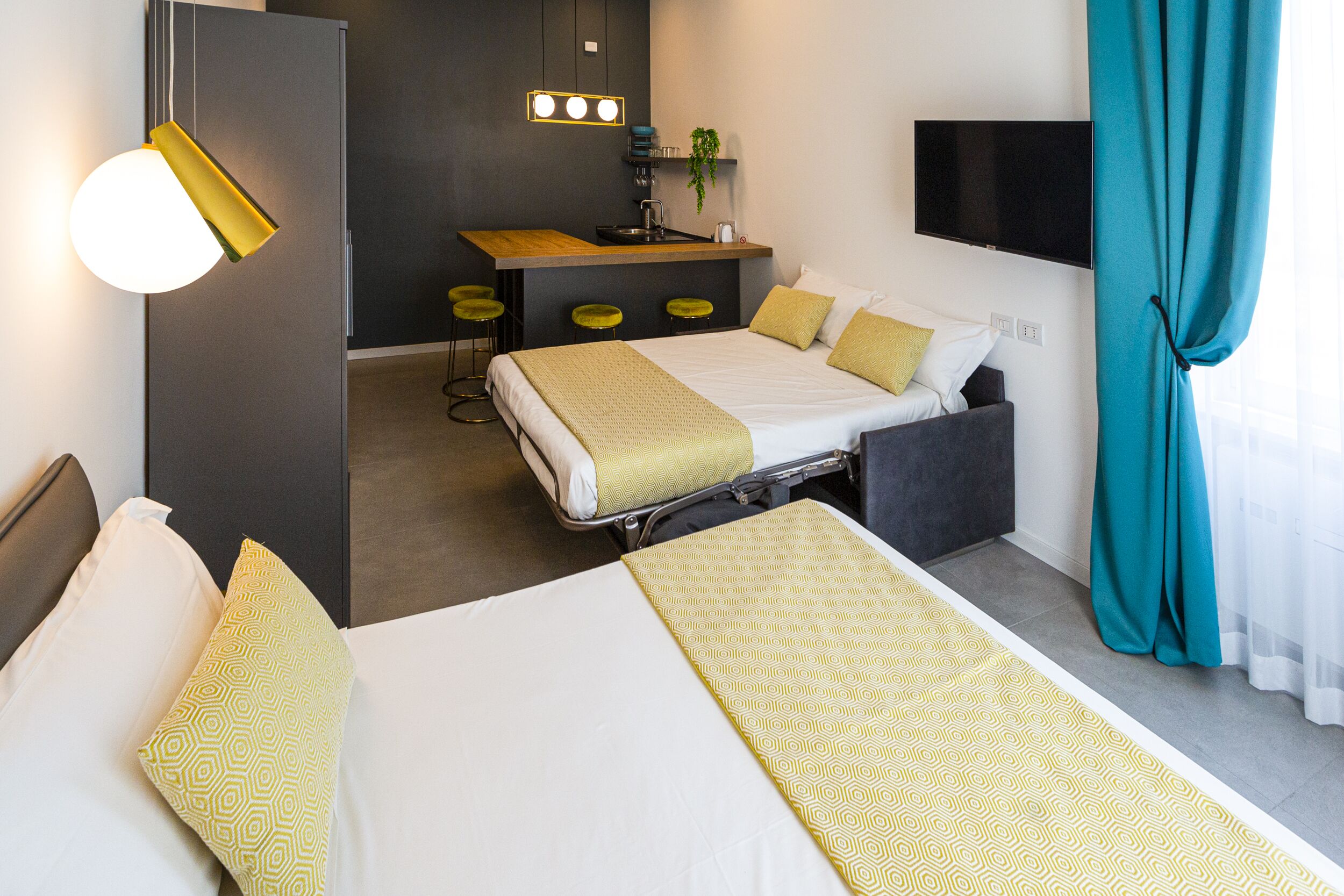 A hotel room with a bed, a desk, and a TV.