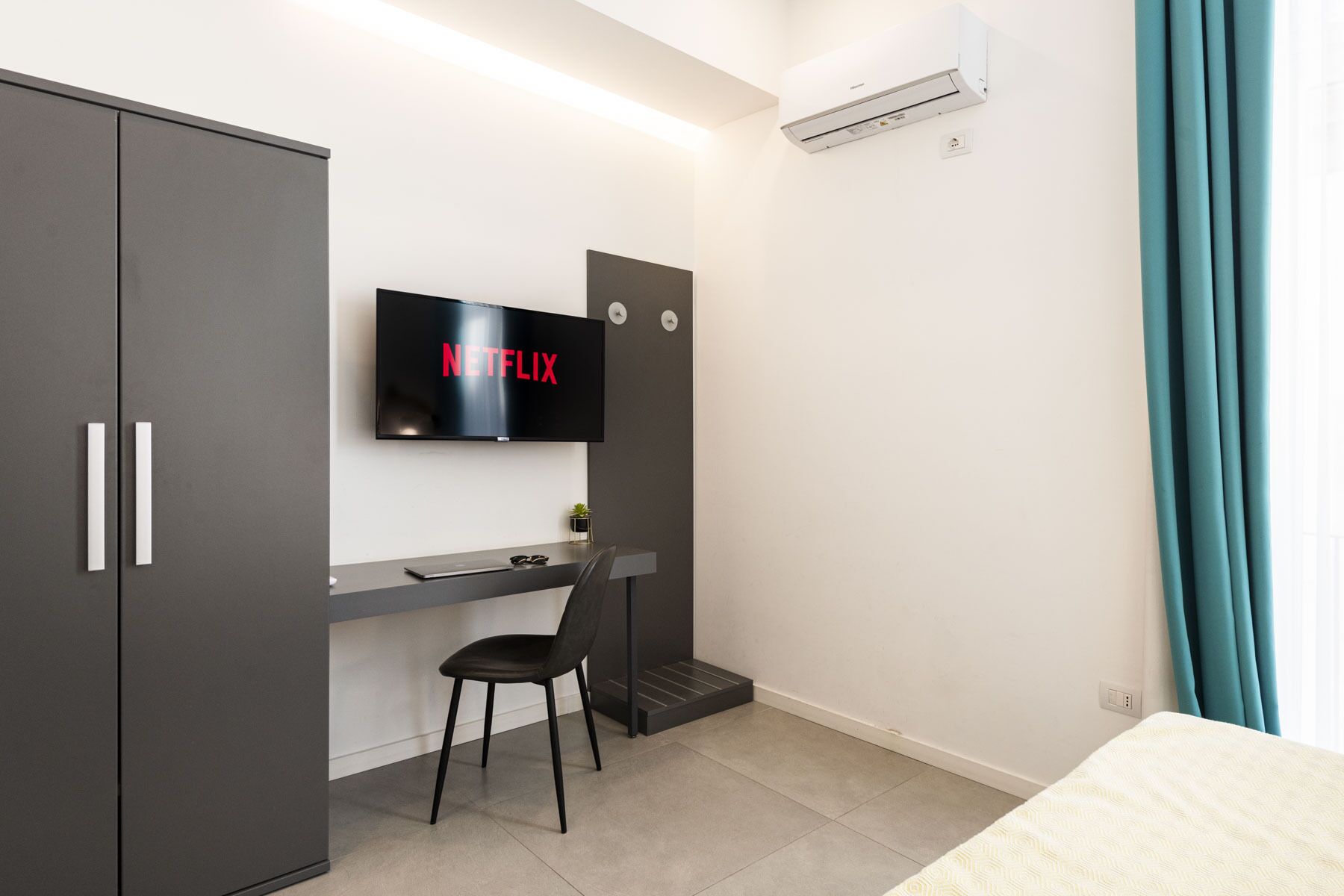 A modern room with a desk, chair, and a TV displaying 'NETFLIX'.