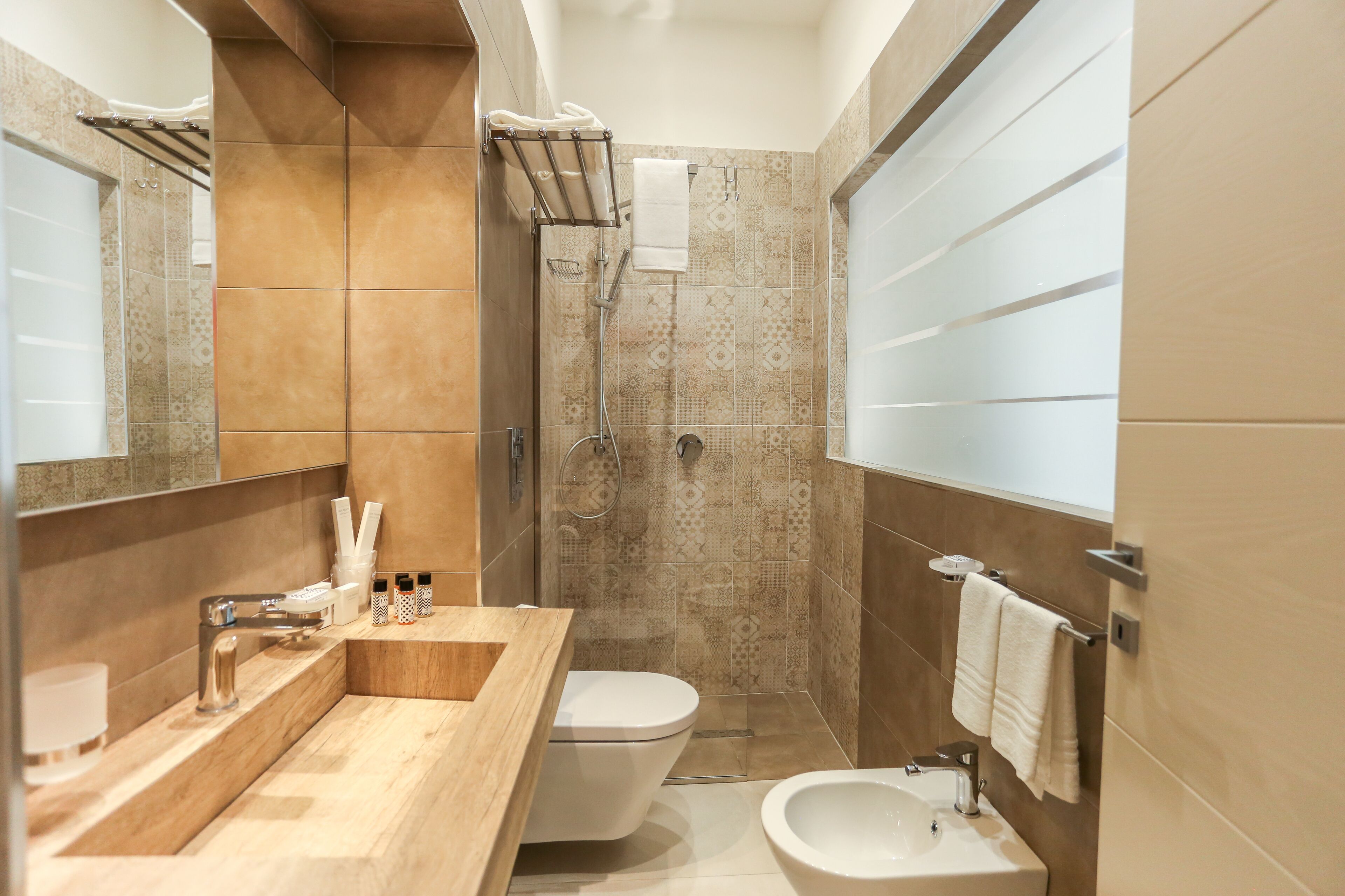 Et moderne badeværelse med et trækommode, toilet, bidet og et stort spejl.