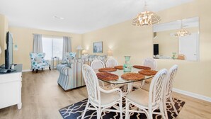 Uma área de refeições com mesa de vidro, cadeiras de vime e um lustre.