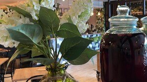 Een restaurantinterieur met een tafel, stoelen, een vaas met witte bloemen en een potje jam.