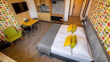 Una camera d'albergo con un letto, una scrivania, una sedia, una televisione e un armadio.
