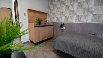 Un dormitorio con una cama, una mesita de noche de madera, un lavabo y un papel tapiz con estampado geométrico.