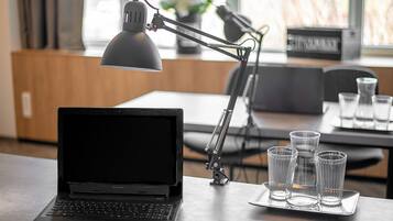 A laptop on a table with a desk lamp and three glasses.