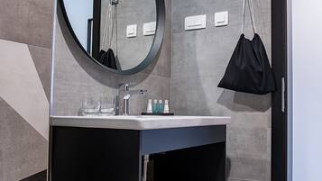 A modern bathroom with a round mirror, a sink, and a towel rack.