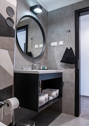 Une salle de bain moderne avec un miroir rond, un lavabo et un porte-serviettes.