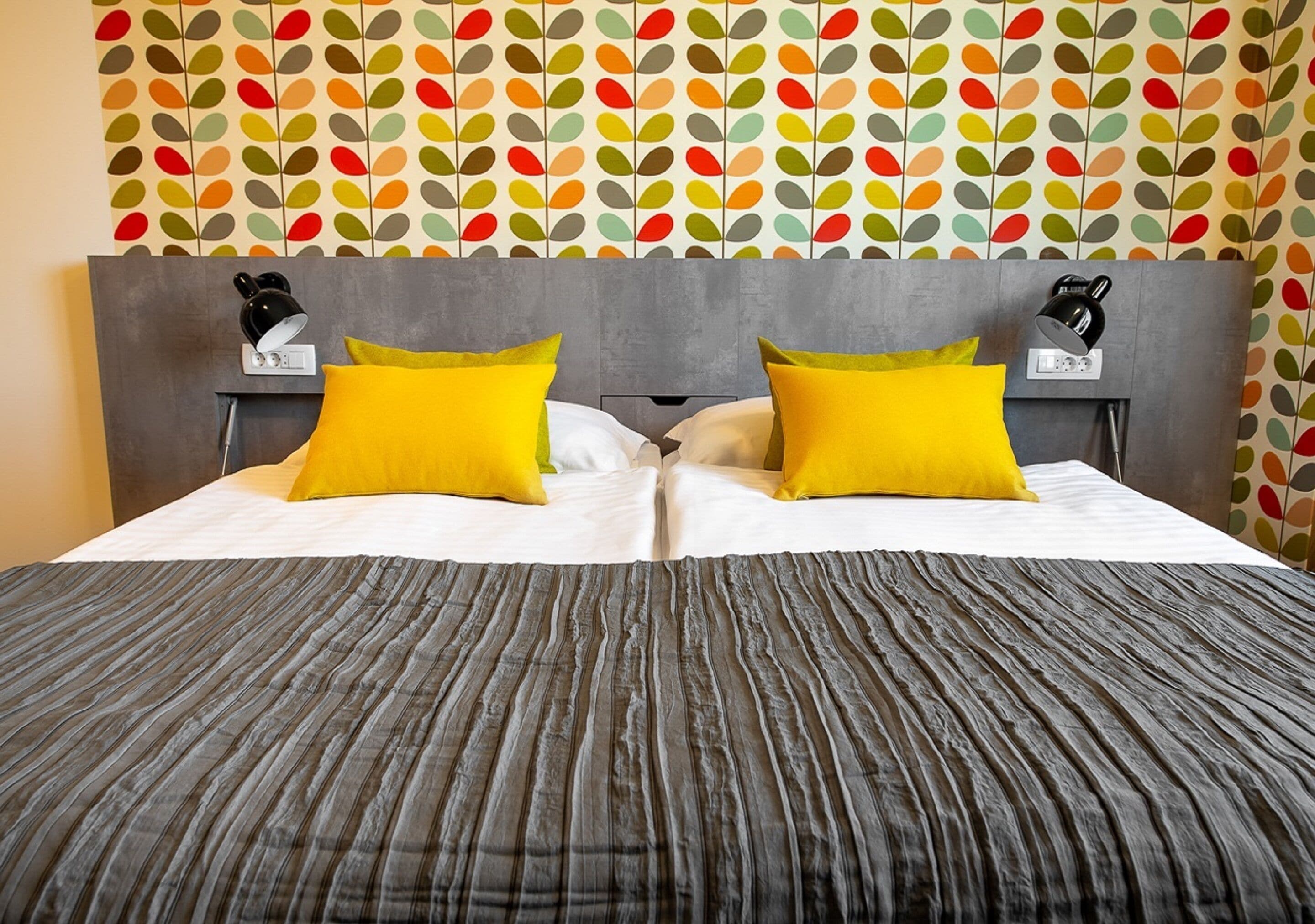 A neatly made bed with a striped bedspread, two pillows, and two bedside tables with lamps.