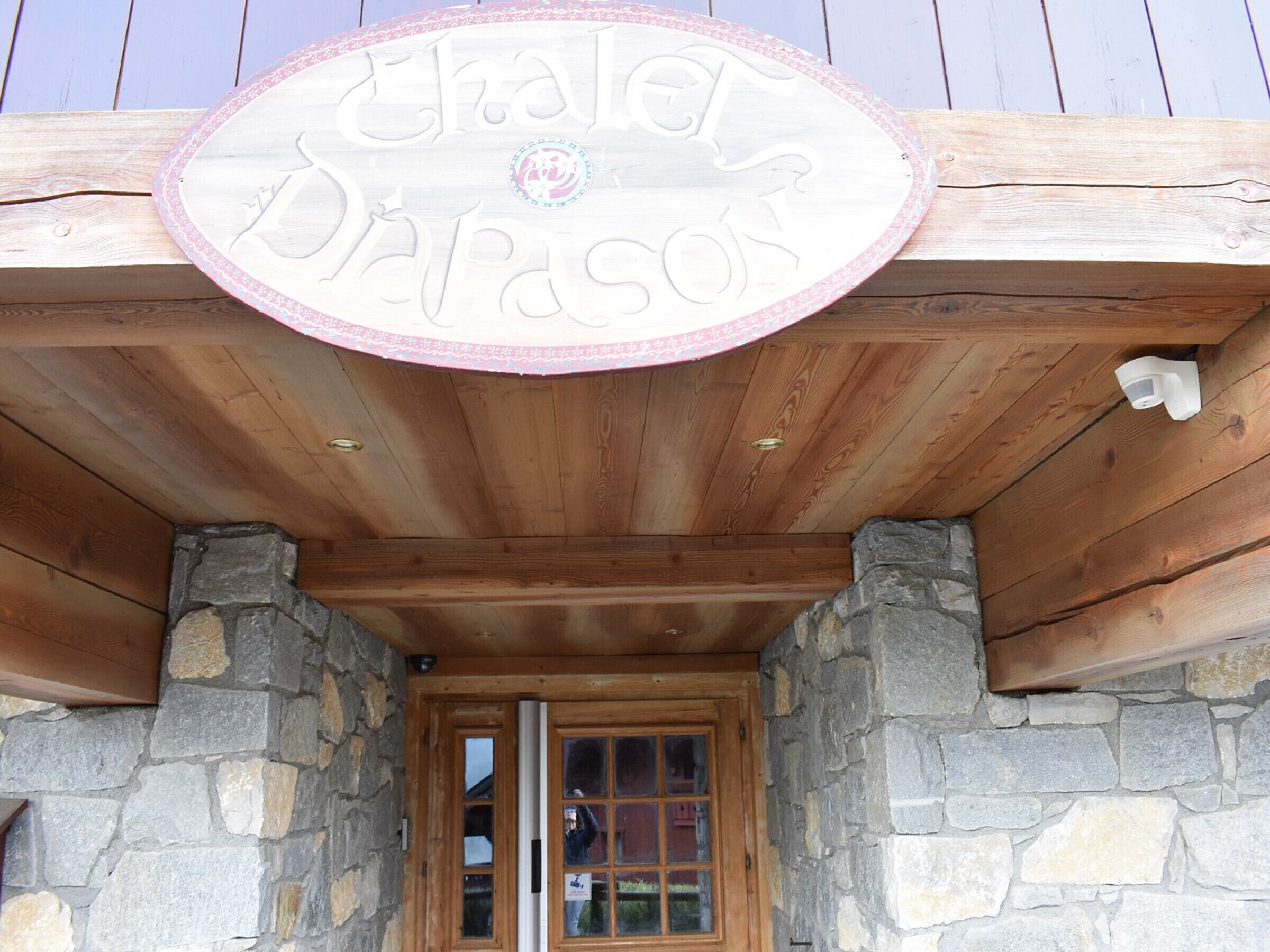 A wooden building with a stone facade and a sign above the entrance.
