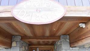 A wooden building with a stone facade and a sign above the entrance. - Meribel: Spacious 3BR Apartment, Sleeps 6, 150m from Ski Lift, Free Shuttle & Covered Parking (Méribel)