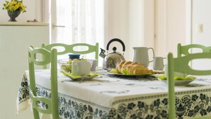 A dining table with a floral tablecloth, green chairs, and a tea set. - Ariston Vacanze Residence (Ravenna)