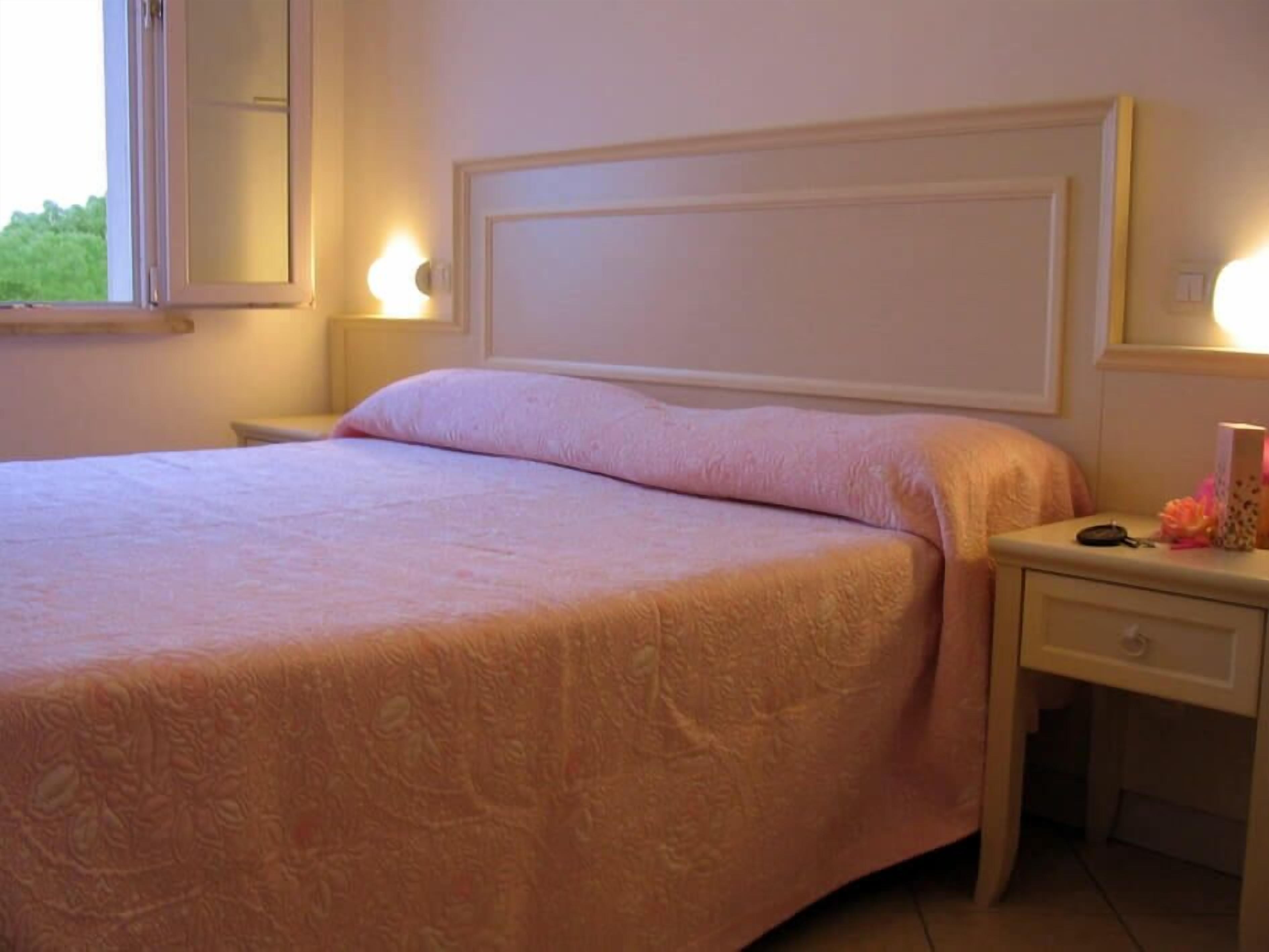 Une chambre à coucher avec un lit, des tables de chevet, un miroir et une fenêtre.