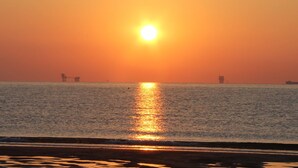 A sunset over a calm sea with distant offshore structures. - Ariston Vacanze Residence (Ravenna)