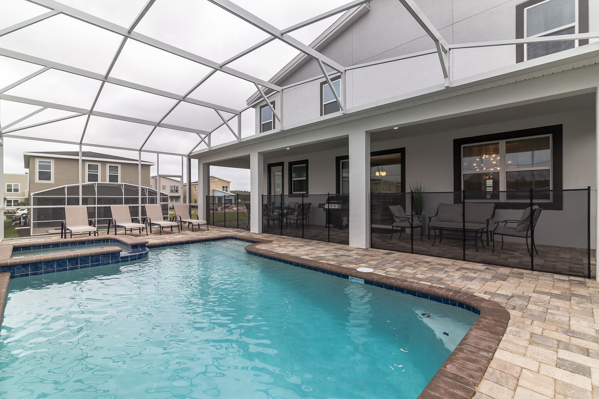A swimming pool with a glass ceiling, outdoor seating, and a patio area.