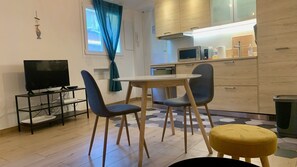 A compact living space with a dining area, a TV, and a kitchenette.