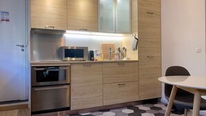 A compact kitchen with a microwave, oven, and a small dining area with a chair.