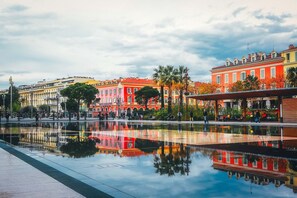 A reflective water feature in a public square with colorful buildings in the background.