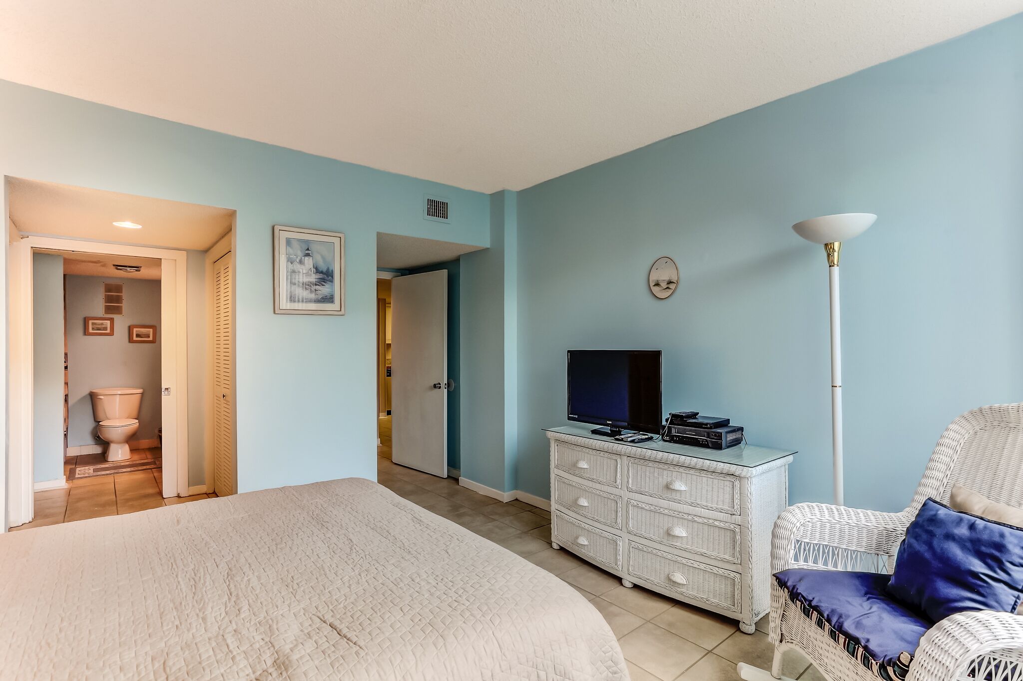 Ein Schlafzimmer mit Bett, Kommode, Fernseher und Stuhl.