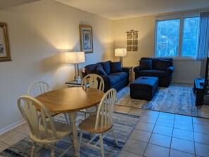 Un salon comprenant une table à manger, deux canapés et un téléviseur.