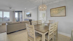 Una sala de estar moderna con comedor, ventilador de techo y un amplio ventanal con persianas.