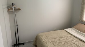 Un dormitorio con cama, una lámpara de pie y un enchufe de pared.