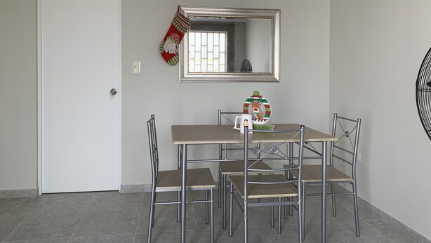 Un comedor con una mesa, sillas, un espejo y un plato decorativo.
