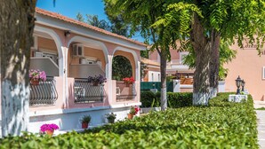 Un edifici amb façana rosa, balcons arquejats i plantes en testos.