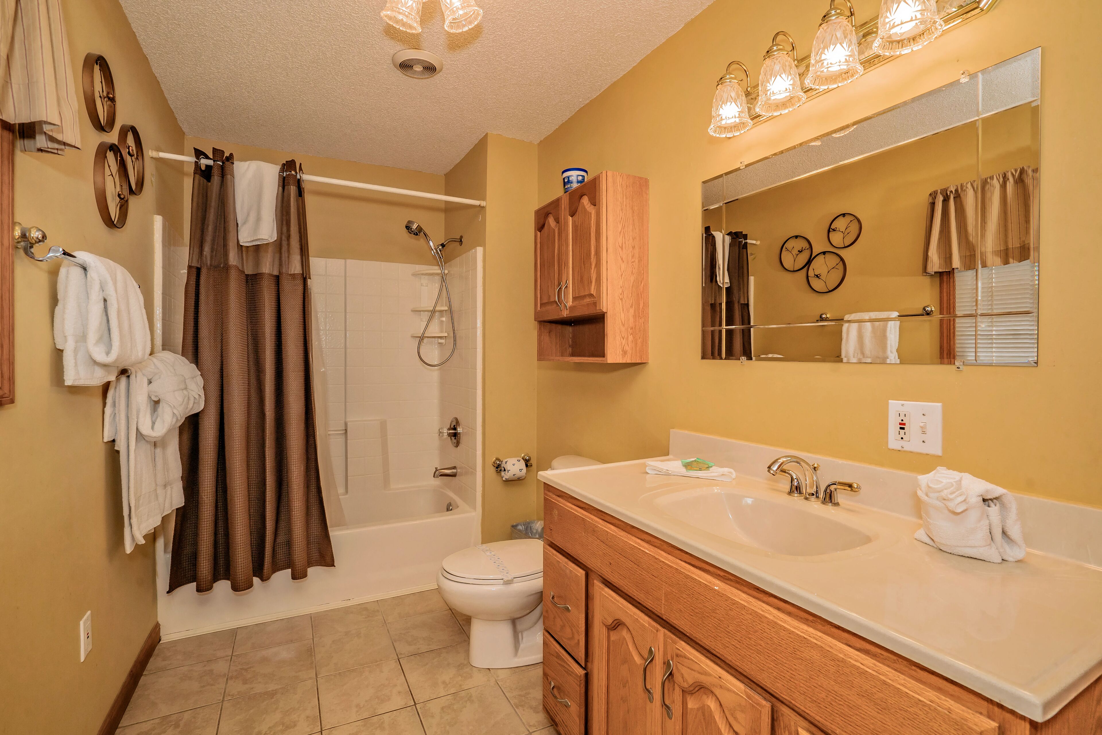 A bathroom with a bathtub, toilet, vanity with a sink, and a large mirror.