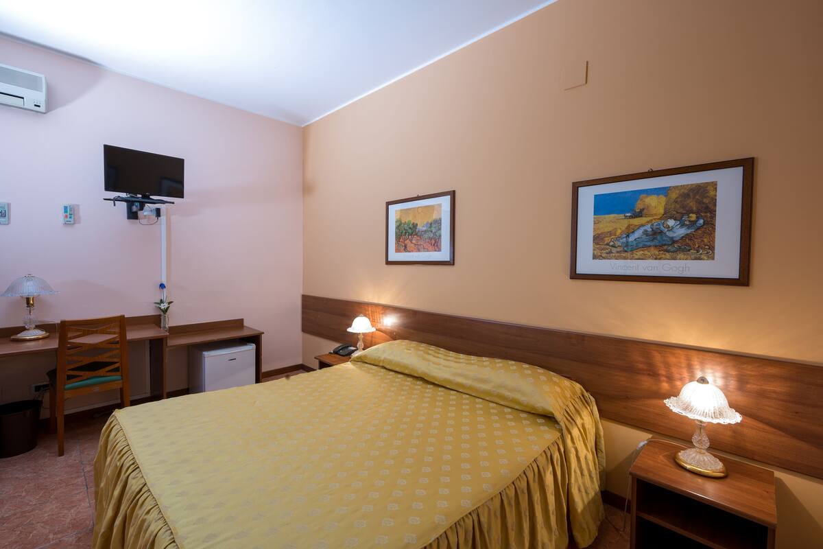 Ein Hotelzimmer mit Bett, Schreibtisch, Stuhl und zwei Wandleuchten.
