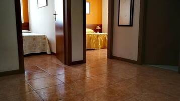 A hallway leading to a bedroom with a bed, a nightstand, and a lamp.