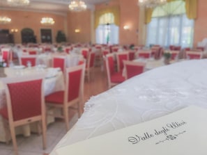 Une salle de banquet où les tables sont dressées pour un événement officiel.
