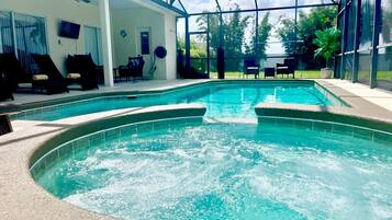 A swimming pool with a hot tub in the center, surrounded by lounge chairs and a glass-enclosed patio.