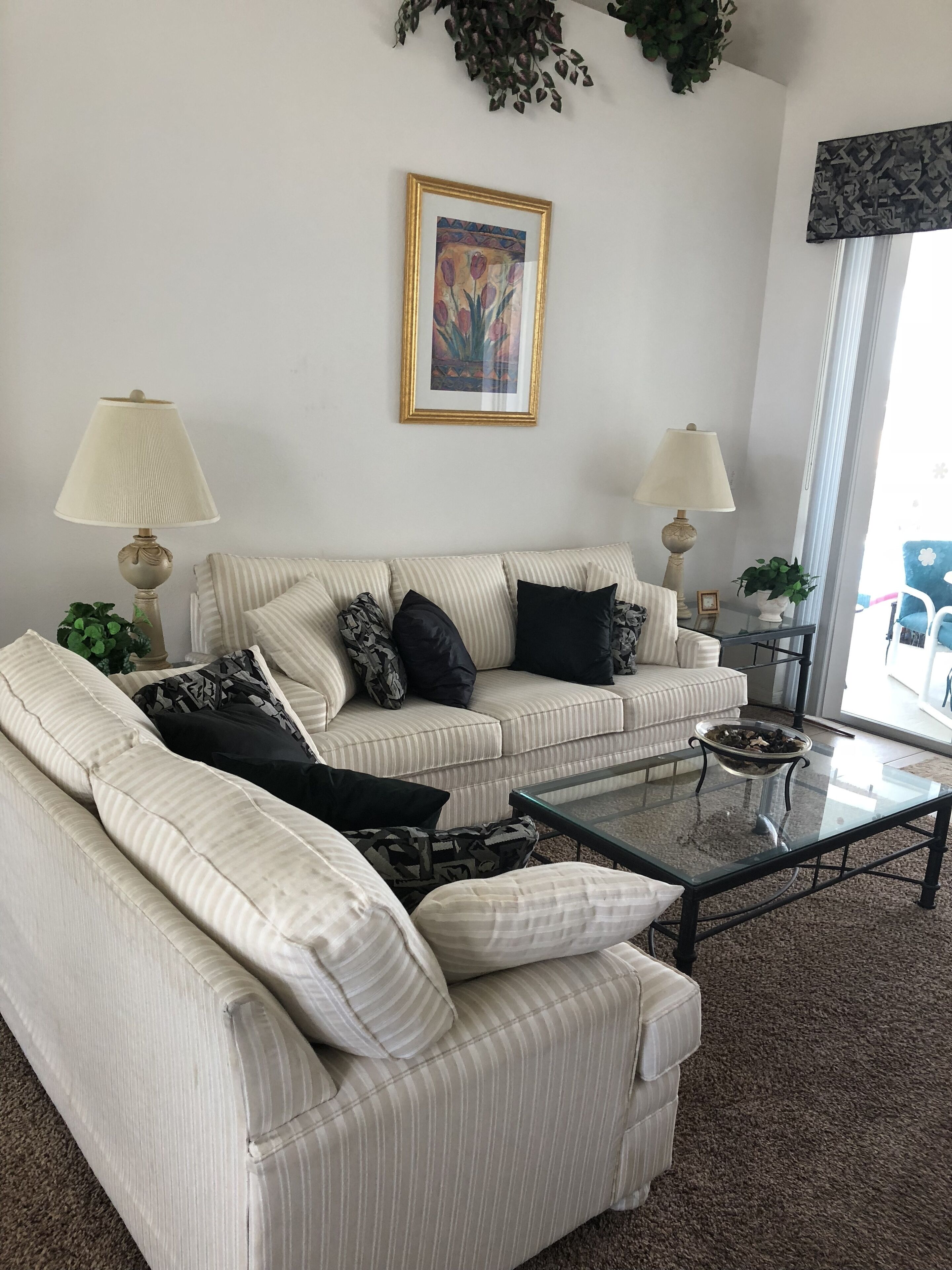 A living room with a striped sofa, two lamps, a coffee table, and a framed picture on the wall.
