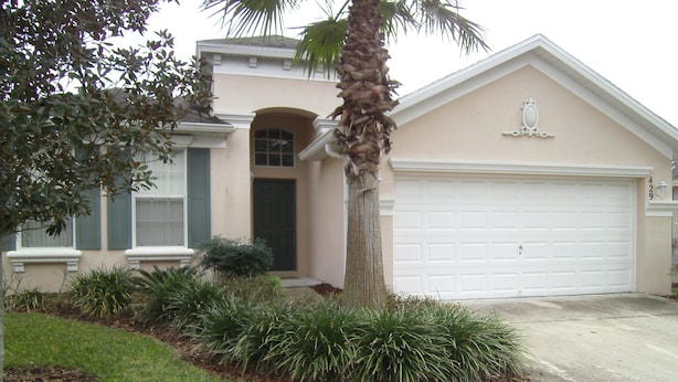 A residential house with a garage, a front door, and a well-maintained lawn. - Orlando Renters (Davenport)