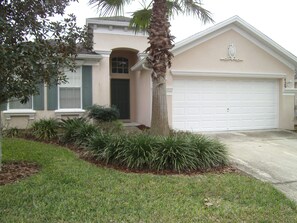 A residential house with a garage, a front door, and a well-maintained lawn. - Orlando Renters (Davenport)