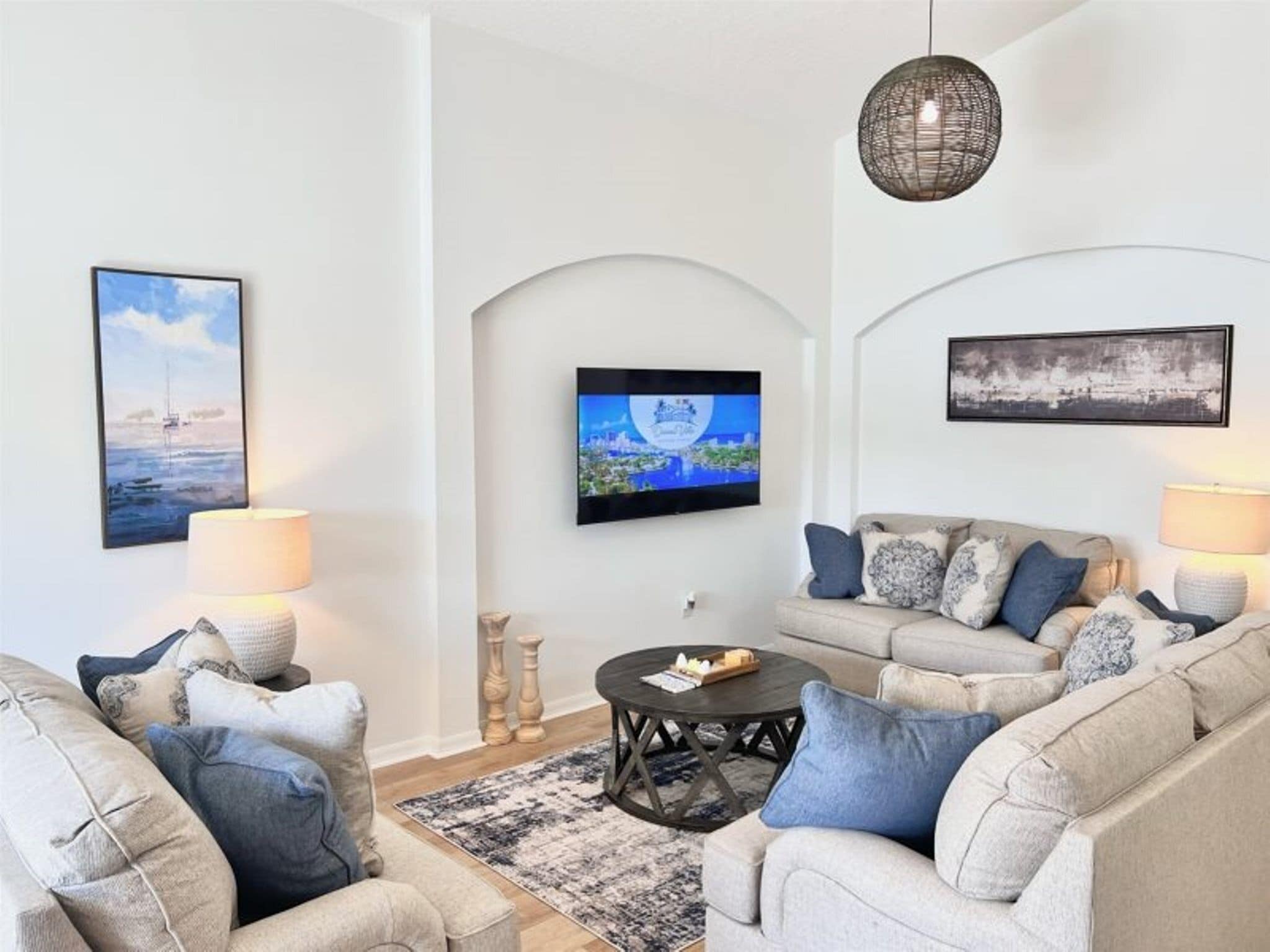 A modern living room with a sofa set, a coffee table, and a TV mounted on the wall.